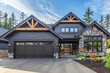 Luxurious new home with a contemporary design, featuring a two-car garage, surrounded by rich charcoal gray siding and a natural stone wall trim for a distinguished appearance.