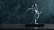 A dark, matte background showcasing a platinum atom model trophy