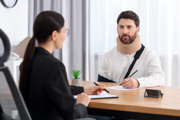 Canvas Print - Injured man signing document in lawyer's office, selective focus