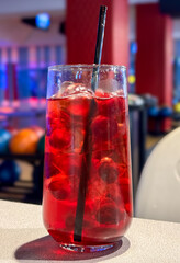 Wall Mural - Cherry drink with ice in a glass on a table in a cafe