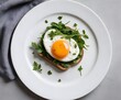 A poached egg topped with fresh herbs and greens, served on a slice of toast and a white plate