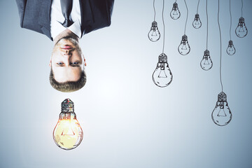 Aufkleber - Upside down portrait of thoughtful man with drawn light bulbs on concrete wall background. Idea, inspiration and think outside the box concept.