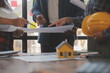 © Sutthicha - A team of construction engineers talks to managers and construction workers at the construction site. Quality inspection, work plan, home and industrial building design project