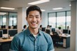 Young asian man smiles brightly in a casual business office setting.