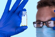 A doctor or professional holds an ampoule. The vaccine in the ampoule in the doctors hand.