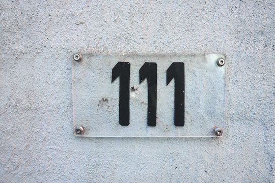 Nummer 111  Hausnummer einhunderteins. Schwarze Ziffern auf einem Plexiglas Schild