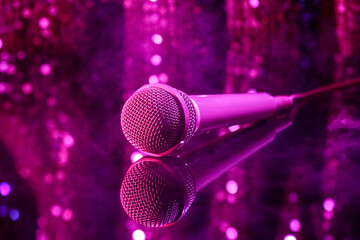 Wall Mural - Modern microphone on glass table against blurred lights, closeup