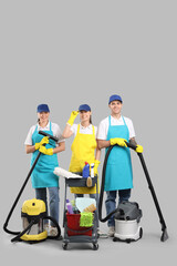 Poster - Workers of cleaning service with supplies on light background