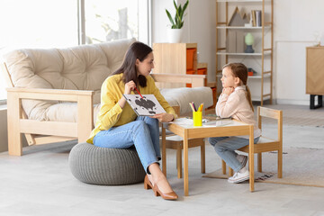 Poster - Female psychologist showing picture to little girl at table in office