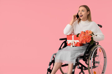 Canvas Print - Young woman in wheelchair with roses and gift talking by mobile phone on pink background. International Women's Day