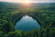 Aerial view of the perfectly circular lake nestled in an endless forest, bathed in golden sunlight, surrounded by dense green trees. Created with Ai
