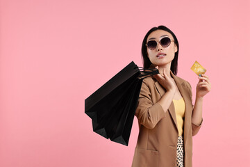 Sticker - Beautiful woman with shopping bags and credit card on pink background. Space for text