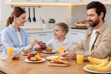 Canvas Print - Happy family having breakfast at table in kitchen