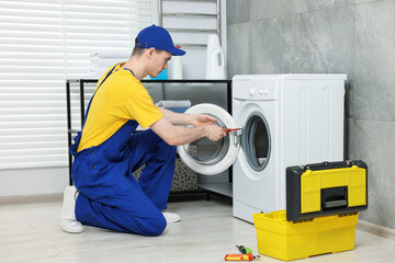 Wall Mural - Young plumber repairing washing machine in bathroom