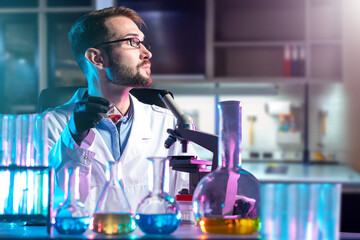 Poster - man microbiologist. laboratory assistant with microscope and flasks. multi-colored reagent on microb