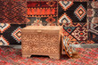 Traditional Asian wooden chest with carved ornaments against the background of carpets in a yurt - the dwellings of nomads. Close-up