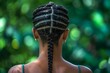Close-up of a woman's elaborate braided hair captured against a serene, bokeh green background. Back view