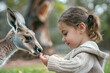 Little girl feeding and taming cute kangaroo in the park
