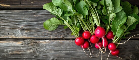 Wall Mural - A bunch of radishes with vibrant green leaves resting on a wooden table, ready for culinary use.