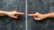 Two hands pointing at each other, on black background with white demarcation line, concept image