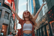 © ReisMedia - Portrait of a young cheerful girl with her hands raised up against the backdrop of city streets. Summer time