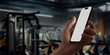 CU Caucasian man using phone in a gym, coaching training sports app mockup
