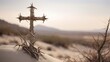 christian cross woven with thorny branches against a barren landscape
