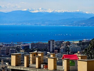 Wall Mural - Genova, Italy - March 24, 2024: Aereal view to the city of Genoa with beautifull blue sea in the background. Sunny spring day over the city. Modern and old architecture mix.