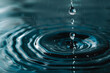 a droplet of water falling into a pool, creating ripples on the surface