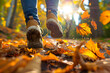 a person's feet kicking up autumn leaves in a park