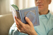 © TSViPhoto - Lifestyle portrait of senior islamic man reading Quran at home. Natural aesthetic light