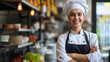 A female chef smiling in her kitchen with her arms crossed