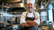 A smiling chef in his kitchen with his arms crossed