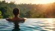 A woman in a swimming pool looks at the forest in front of her at sunset