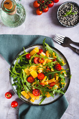 Wall Mural - Dietary salad of orange slices, cherry tomatoes and arugula on a plate  top and vertical view