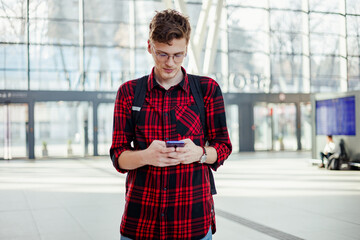 Wall Mural - Passenger with backpack standing at train station and typing on phone