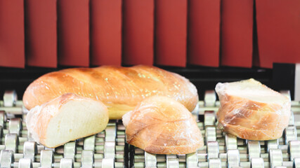 Poster - A row of bread loaves are on a conveyor belt, with one loaf missing a piece