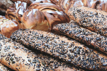 Poster - A variety of baked goods, including bread and pastries, are displayed on a table. The bread has a nutty flavor and is covered in seeds, while the pastries are sweet and flaky