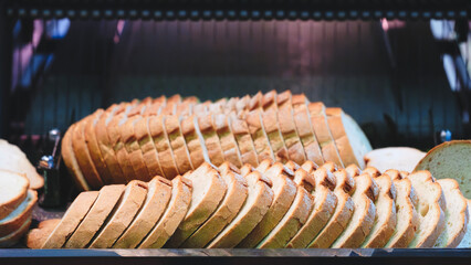Poster - A row of bread loaves are on a conveyor belt, with one loaf missing a piece