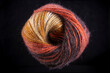 A ball of yarn with a brown, orange, and black color. The yarn is twisted and knotted