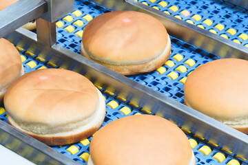 Poster - Conveyor belt next to a hamburger bun. All buns are divided into halves of the same size and shape and are packed in packaging film for sale or transportation.
