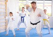 Children with parents in kimono standing in fight stance during group karate training