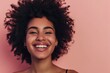 Portrait of a beautiful young african american woman with afro hairstyle smiling against pink background