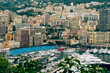 A scenic view of Monte Carlo harbor, with a diverse array of moored yachts and a vibrant tapestry of urban architecture rising on the hillsides