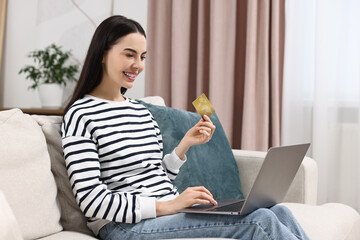 Wall Mural - Happy young woman with credit card and laptop shopping online at home