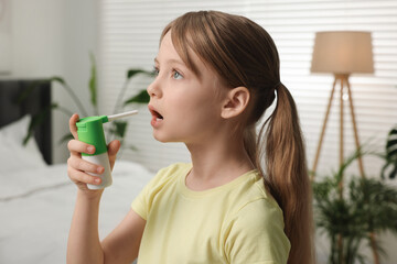 Canvas Print - Little girl using throat spray at home