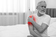 © New Africa - Arthritis symptoms. Man suffering from pain in his shoulder indoors, space for text. Black and white effect with red accent in painful area