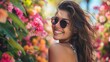 A cheerful portrait of a beautiful smiling brunette young natural woman wearing sunglasses, surrounded by colorful blooms in a botanical garden, exuding joy and vitality
