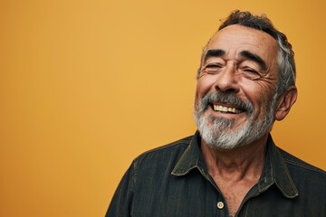 Wall Mural - Portrait of an old man with a gray beard and mustache looking at the camera on a yellow background