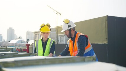 Wall Mural - Professional Asian man and woman teamwork engineer and foreman using blueprint working outdoor at construction site building rooftop. Architecture inspector inspect building exterior structure system.